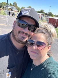 a man and woman posing for a photo in a parking lot